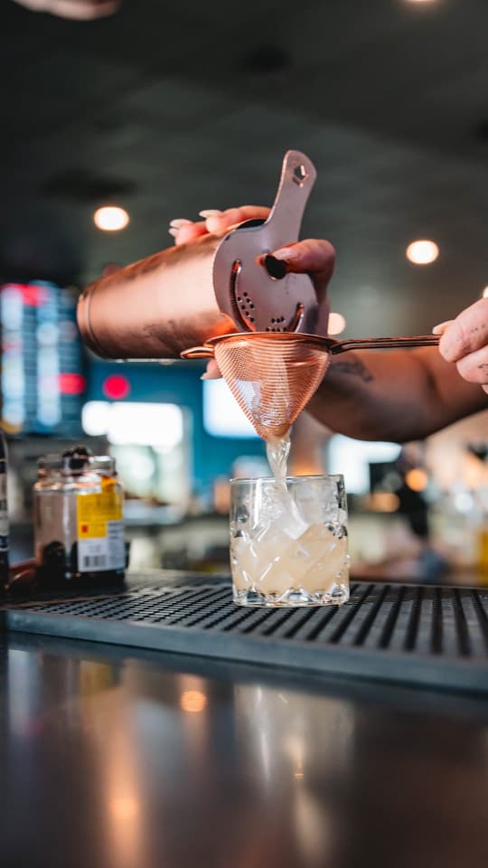 A copper cocktail shaker mid-pour at Twisted Pin's bar