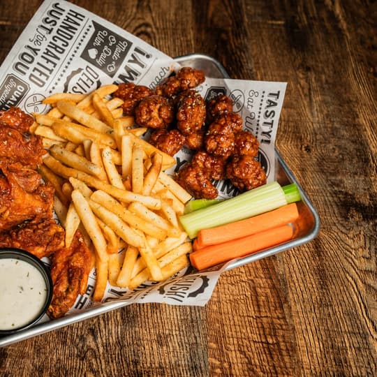A platter of wings, fries, celery, and carrots at Twisted Pin